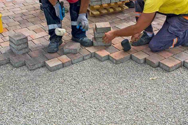 Concrete contractors installing paver driveway edge with gravel base preparation in Beachwood, OH