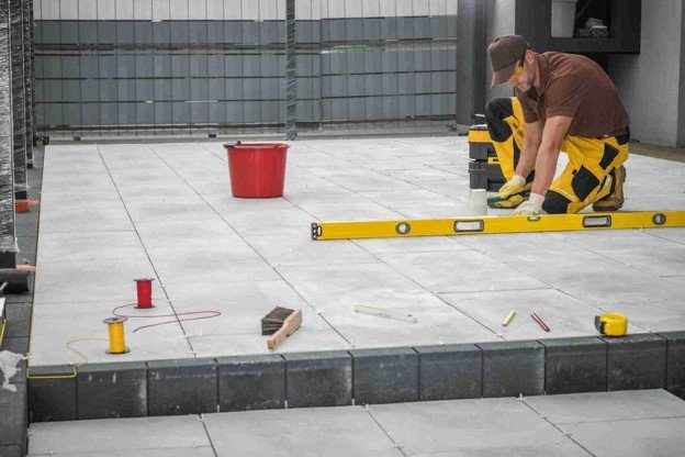 Contractor using a level tool to align large concrete patio slabs during installation in Beachwood, OH