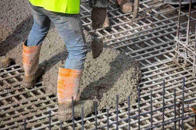 Worker pouring fresh concrete over steel rebar grid for structural slab construction in Beachwood, OH